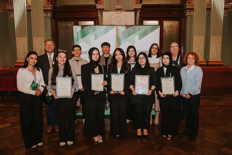 A group of staff and students stand holding their public education foundation scholarships