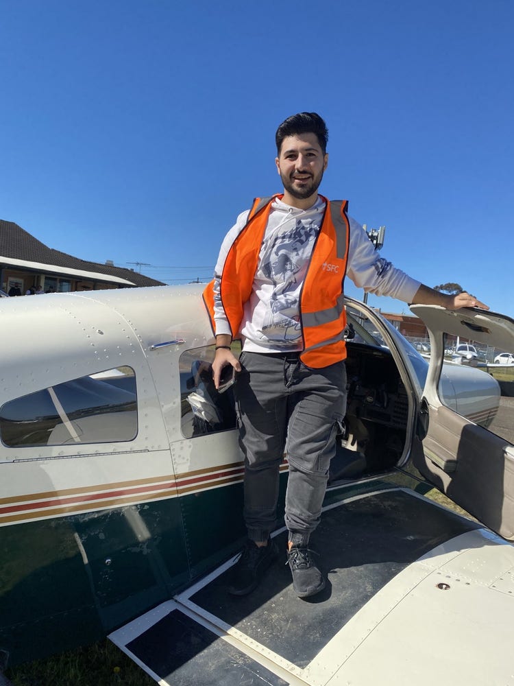 Students exits a small aircraft wearing a hi-visibility vest.