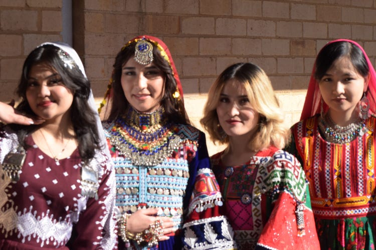 A group of four female students stand dressed in traditional Afghan clothing
