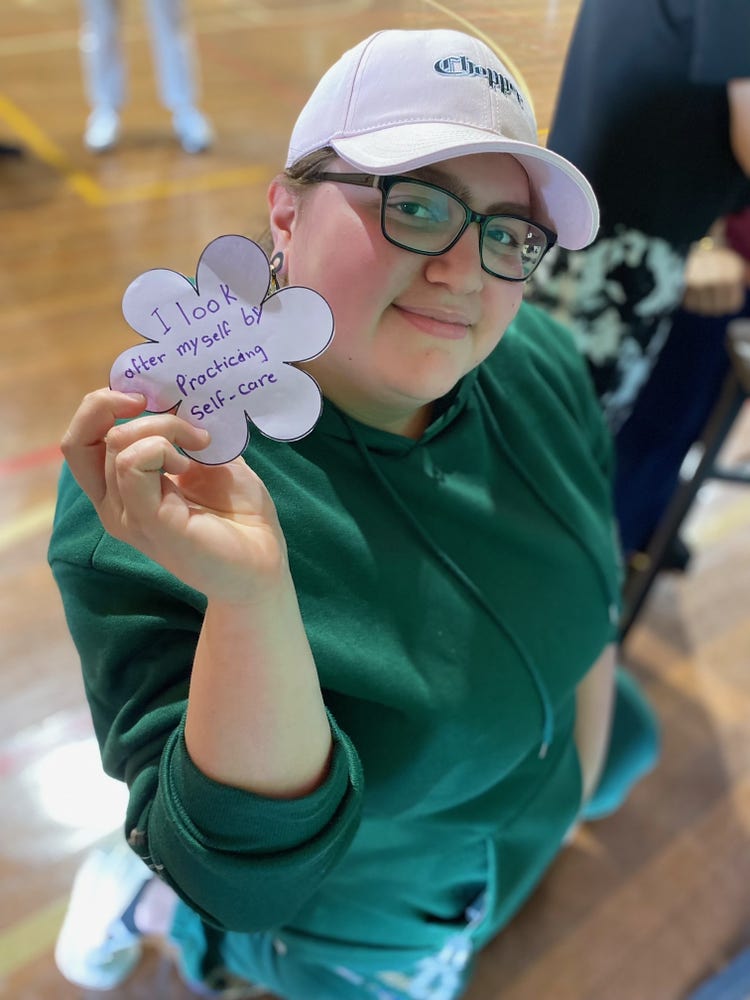 A student holds up a handwritten positive note of affirmation